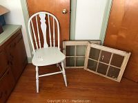 Image showing white spindle back chair beside two antique wooden window frames with six panes each on wooden floor.