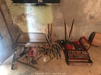 Overview of hand tools laid out on floor including pliers, screwdrivers, hammers, wrenches, and one toolbox