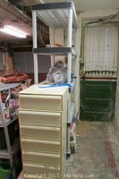 Photo showing seven beige stackable storage drawers and tall plastic shelf unit behind them in a basement storage area.