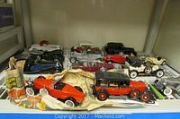 Shelf view showing all 13 Franklin Mint car models on newsprint