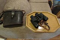 Canon 8x30 vintage binoculars with leather case on a beige textured fabric surface, and a small wooden clamp on a wooden tray.