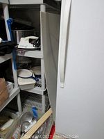 Plastic shelving unit with kitchen items including iron, containers, pans