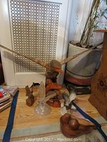 Large wood eagle carving with wide wingspan alongside smaller bird figurines and wood dish with carved fruits on floor.