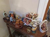 Overview of assorted handpainted Ukrainian eggs arranged on a table, including eggs in a white porcelain basket, display stands, and glass cloches.