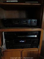 Sony stereo components and KLH Audio Systems receiver in wooden shelves, showing front view of cassette deck on top and CD changer and receiver below.