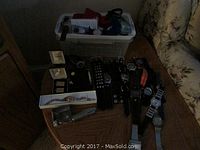 Assortment of men's watches displayed on wooden table with plastic bin in background
