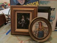 Photo showing the round framed artwork alongside other framed pieces to confirm size and framing details.