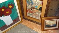 Overview of three framed paintings arranged on floor