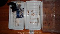 Overhead view of three white trays holding multiple necklaces, a pearl strand, a velvet ring box and other pieces