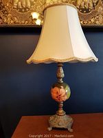 Full view of Moorcroft table lamp with cream scalloped shade and coral hibiscus orb base on wooden surface.