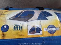 Blue carry bag with yellow label showing image of 6 person dome tent, dimensions, 2 year limited warranty, and Rainguard waterproofing feature.