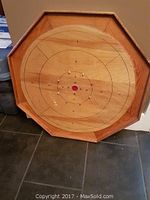Full view of the wooden octagonal crokinole board with playing surface and scoring rings.