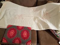 Shows white fabric shower curtain with embroidered cherry blossom design and hand hooked rug with red floral pattern.