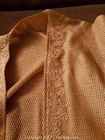 Close-up of the textured fabric and embroidered vertical front panel on the dress.