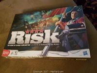 Photo of sealed Risk board game box showing front cover with artwork of military figure and global battle scenes.