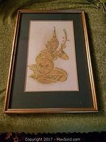 Framed vintage Thai artwork with traditional figure, gold leaf details, green mat, gold frame.