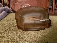 Brown geode slice showing polished face with banded mineral layers and crystal formation inside.