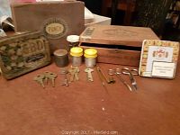 Overview of vintage cigar boxes, cigar tin, keys, film canisters, and scissors arranged on a surface.