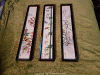 Full view of the three framed Chinese ceramic tiles laid out side by side on a green fabric surface.