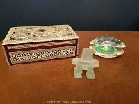 Photo showing the mother of pearl inlaid wooden box closed, highlighting the geometric star pattern on top and sides, with two decorative glass/acrylic objects next to it.
