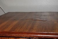 Close-up showing bubbled and worn finish on the wooden top surface of the table.