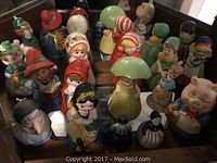 Front view of multiple collectible ceramic character bells arranged closely together on a flat surface showing details and variety of figures.