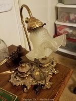Full view of brass desk lamp with vintage frosted glass floral lampshade and ornate base.