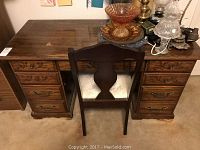 Full front view of the wooden desk and chair showing overall condition and drawer layout.