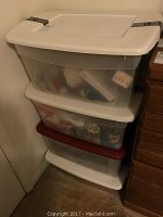 Four stacked plastic bins filled with assorted Christmas decorations showing some wear