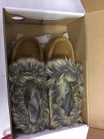 Pair of brown children's moccasins with grey faux fur around ankle in box.