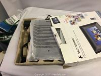 Opened box showing the digital photo frame, interior packaging, and outer box with some product images and branding.