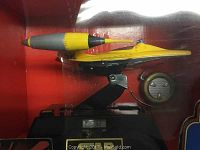 Side view of the yellow and gray Naboo Starfighter mounted on the black alarm clock base, showing the detailed fighter and circular alarm clock dial.