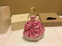 Porcelain figurine of Amelia in pink dress with original box in background.
