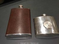 Two flasks side by side: one wrapped in brown leather, stainless steel; the other pewter with Canada leaf emblem