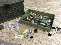 Photo of green vintage sewing box with ornate detailing, open tray with assorted sewing items spread out including threads, buttons, needles, and fabric scraps.