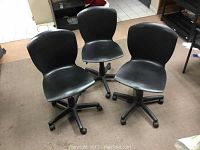 Three black rolling adjustable office chairs grouped showing seat and back design