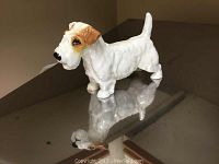 Front angled view of the ceramic dog figurine showing white and brown coloration and glossy finish.