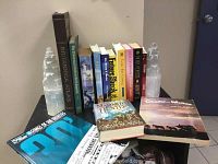 Side view of books placed upright between two clear crystal or glass tentacle-shaped bookends on a black table, with some additional books laid flat in front.