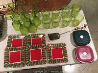 Photo of green bubble textured drinking glasses and wine glasses, plastic food containers with lids, metal flipper, and decorative square plates with holiday patterns.