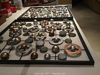 Shown laying on floor side by side to show entirety of metal wall art pieces with spheres and rings in different metallic tones