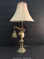 Full view of the elephant double light table lamp with beige lamp shade and elephant figure holding side hanging light.
