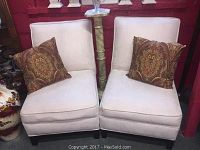Pair of modern ivory microsuede chairs with decorative pillows shown from a front angle.
