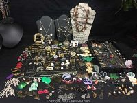 Wide angle photo showing a large amount of vintage jewelry spread out including earrings, brooches, necklaces and bracelets.