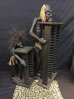 Front angle showing the two tribal wooden CD holders with carved human figures holding the racks, different heights and hair styles visible