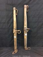 Pair of two wooden horse yokes standing upright showing entire length and iron rings with cloth background.