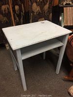 Front view of the antique wooden school desk showing the flat desktop and open shelf underneath, painted in dusty ocean blue.