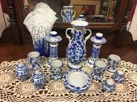 Full set of porcelain pieces arranged on lace cloth in front of a mirror, showing all pieces including the hand blown glass vase