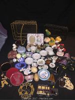 Full layout of assorted vintage collectibles, including tea dishes, figurines, ceramic fruit, and small toys shown on flat surface.