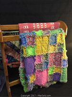 Quilts displayed folded or draped on wooden furniture, showing the colorful patchwork and varied patterns