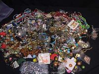 Wide view of bulk assorted jewelry showing multi-colored beads, earrings, pendants, and chains